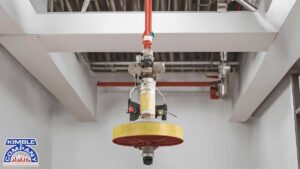 Specialized fire sprinkler maintenance tool attached to a ceiling-mounted sprinkler system.