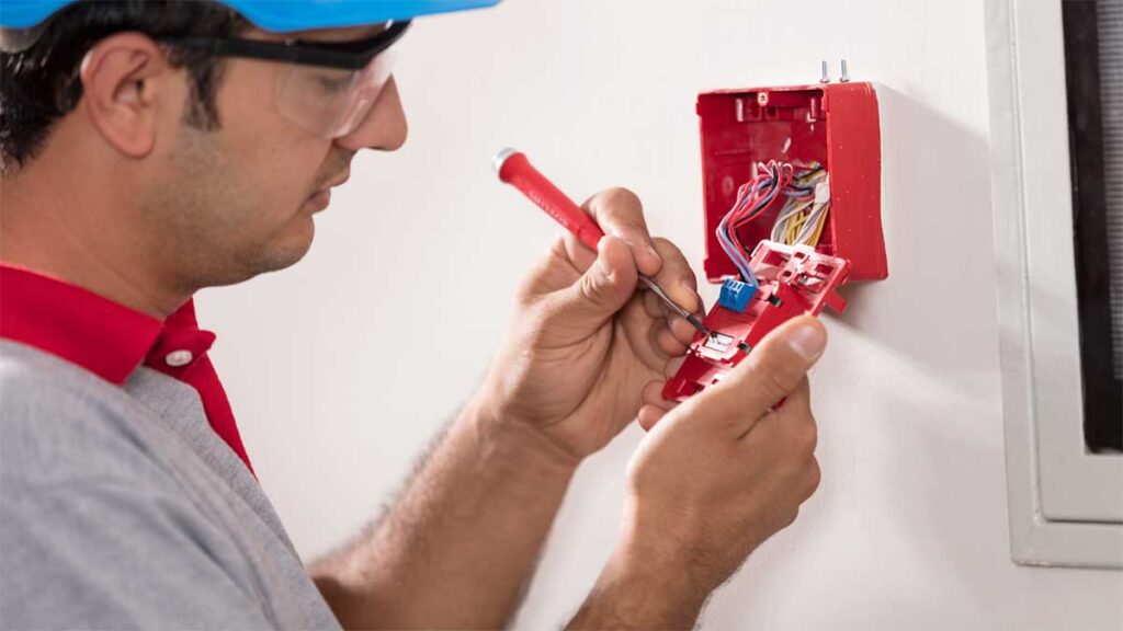 Technician installing wiring in a fire alarm panel.