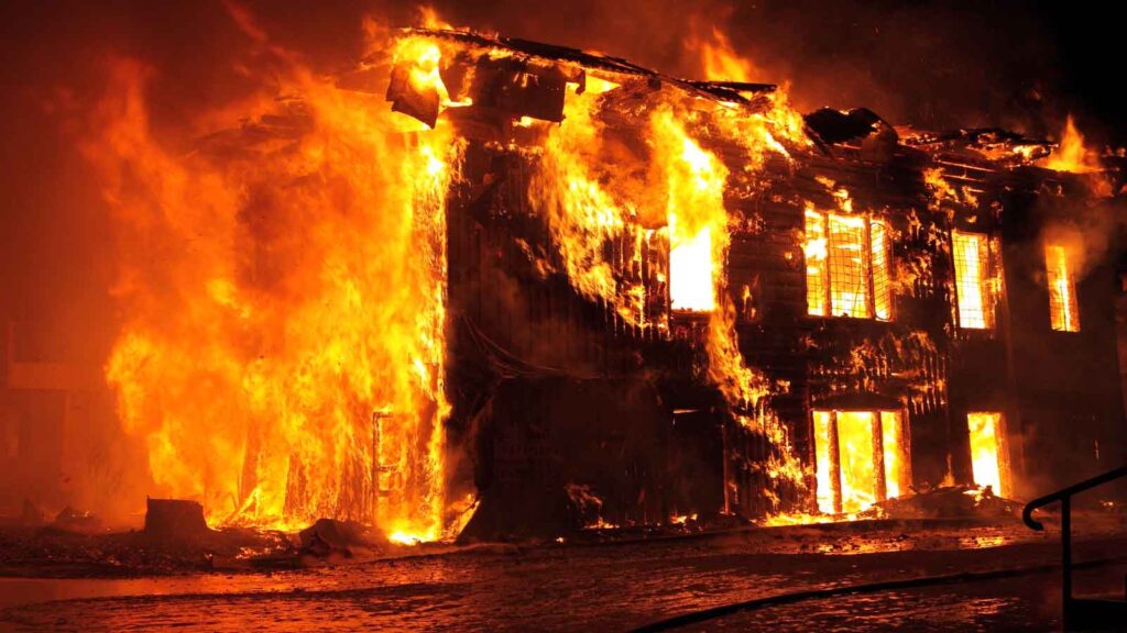 A two-story building engulfed in intense flames at night.