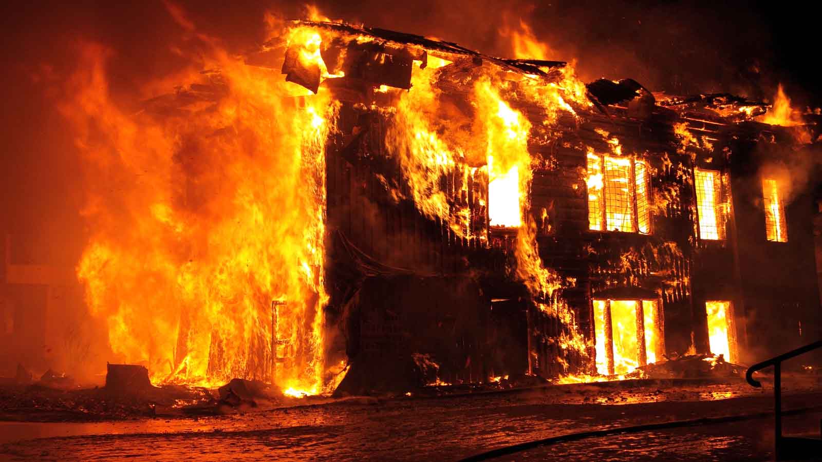 A two-story building engulfed in intense flames at night.
