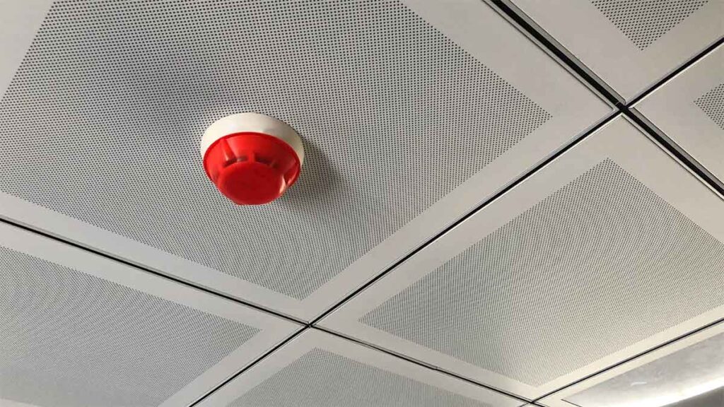 Ceiling-mounted fire alarm sensor in a modern building.