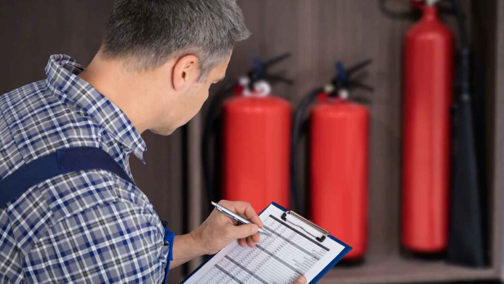 Technician inspecting and recording fire extinguisher details
