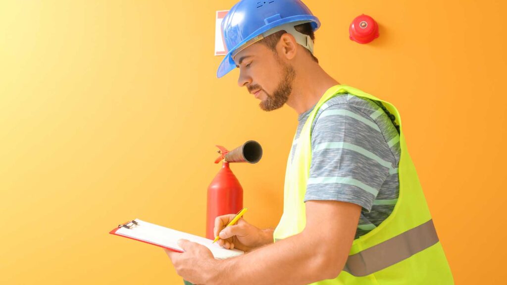 Inspector checking fire safety equipment with a clipboard.