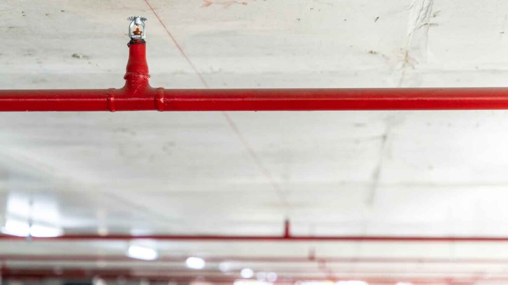 Red fire sprinkler system installed on a ceiling.