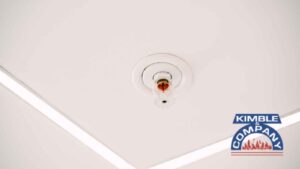 Ceiling-mounted fire sprinkler head in a modern white interior.