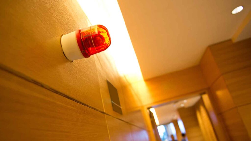 Red emergency alarm light on a wooden wall.