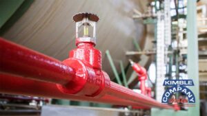 Red fire sprinkler head mounted on a pipe inside a building