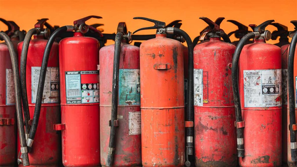 Row of red fire extinguishers with visible wear and tear.