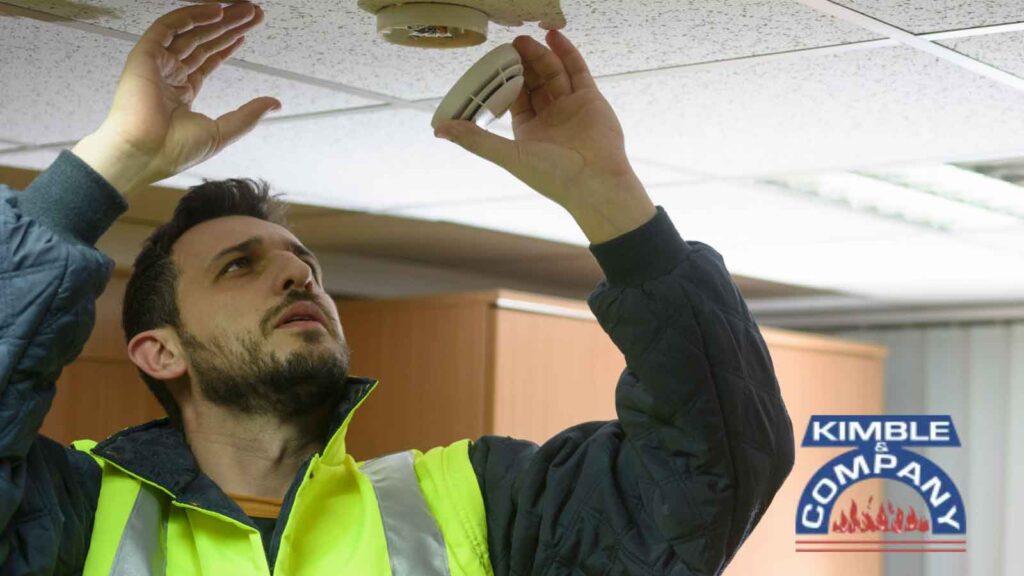 Technician inspecting a ceiling-mounted smoke detector.